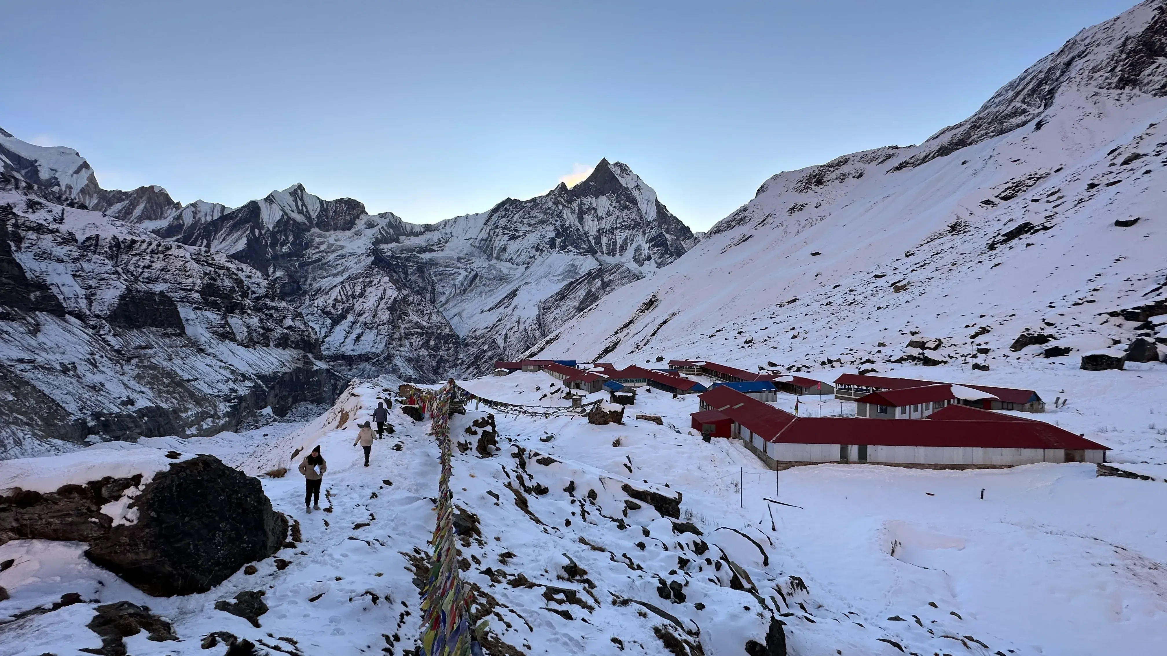 Breathtaking Fishtail peak dominates the view during a 7-day Annapurna Base Camp trek in Nepal. Cozy base camp lodge with iconic red roof awaits.